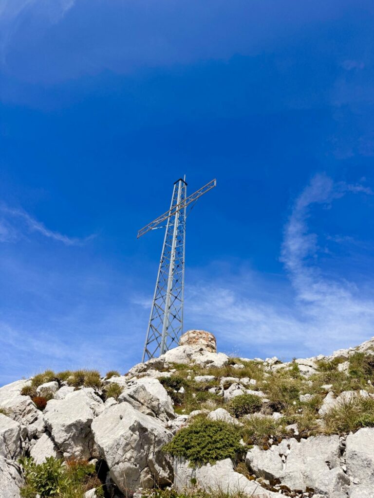 Croix métallique au sommet du Mont Lachat sous un ciel bleu